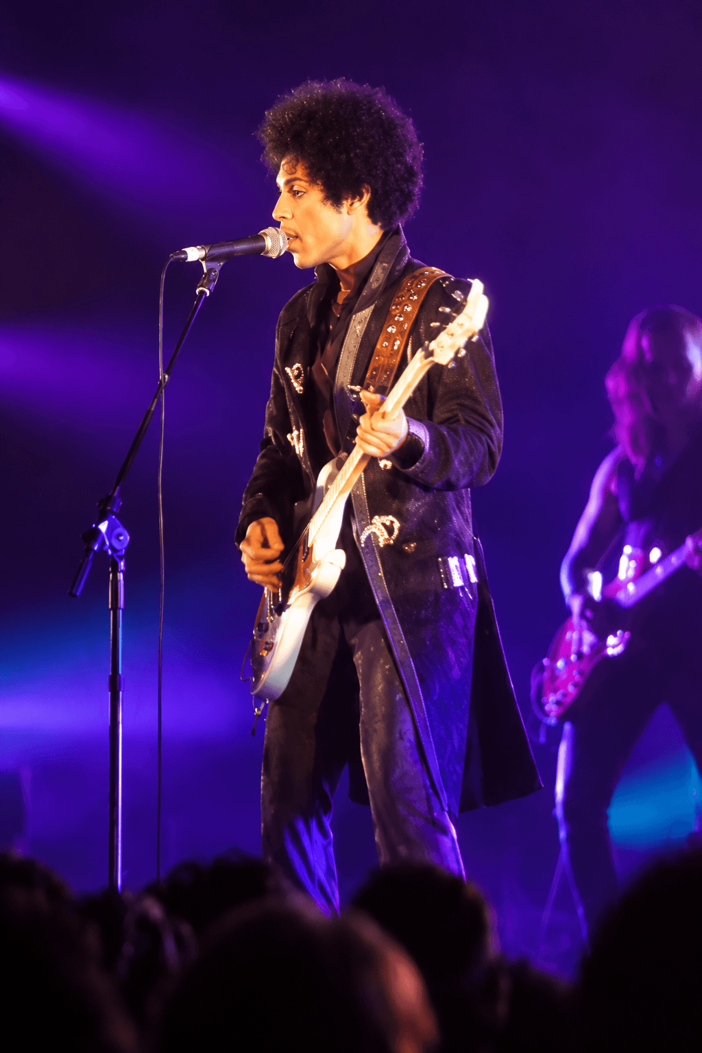 Prince performing onstage under purple concert lights