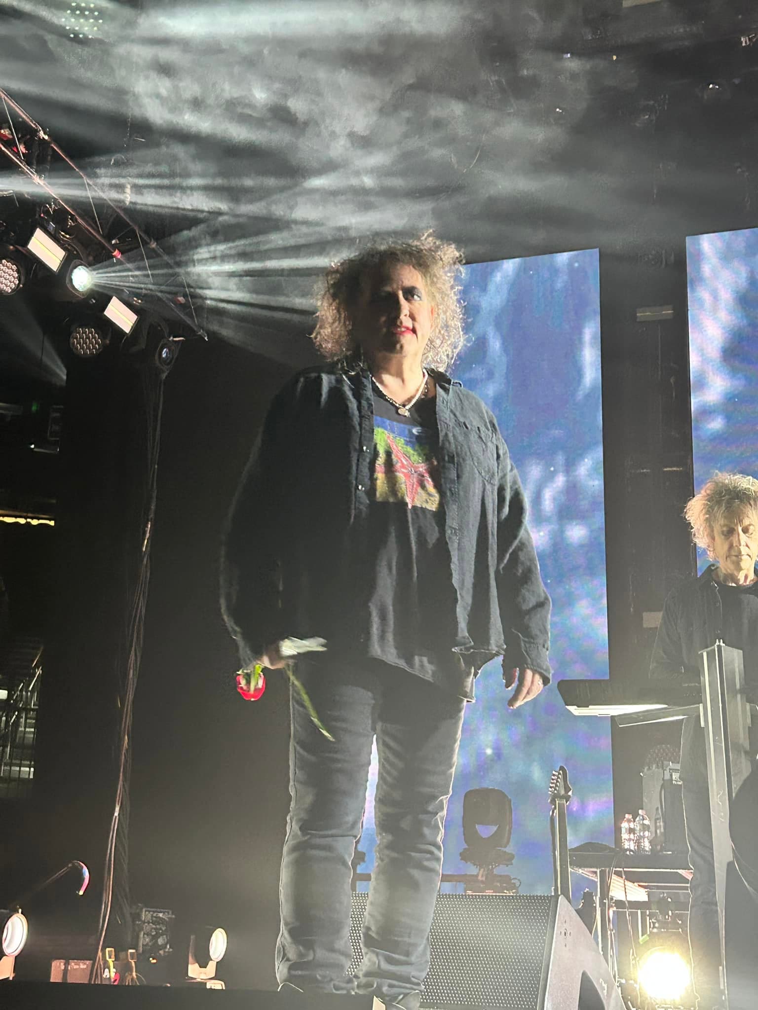 Robert Smith standing at the edge of the stage during The Cure concert